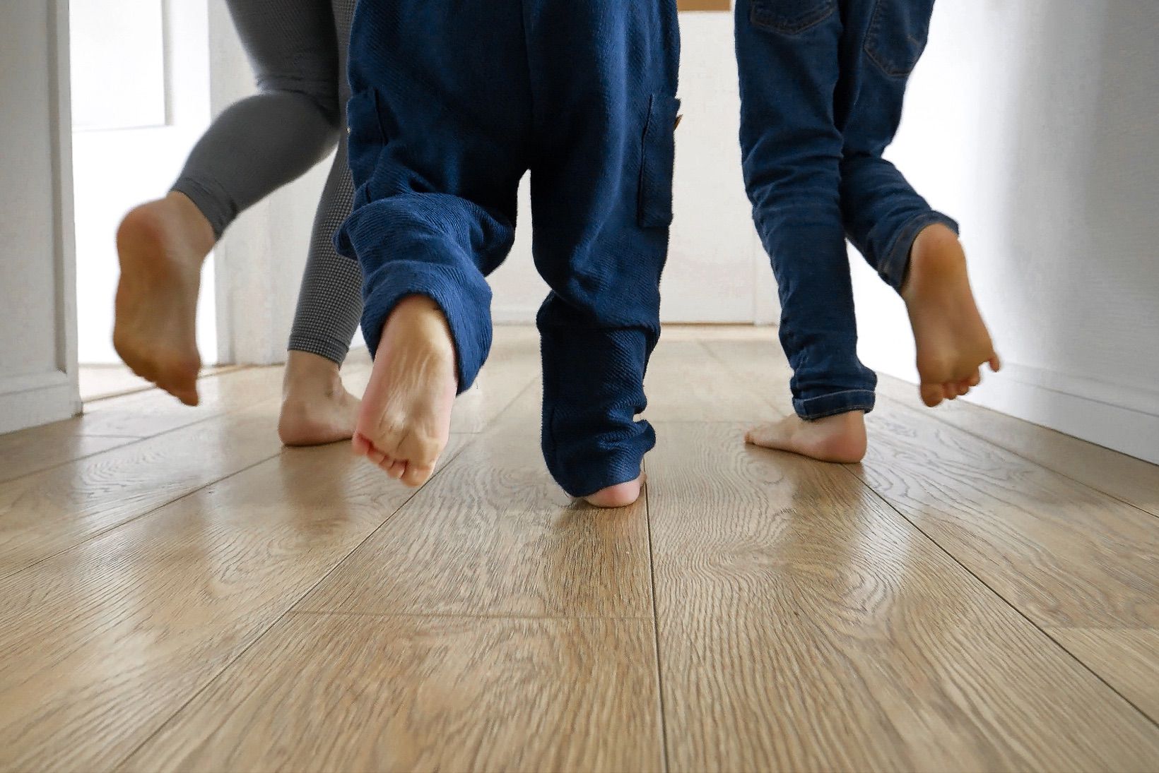 Piedi di una famiglia in corsa su parquet.