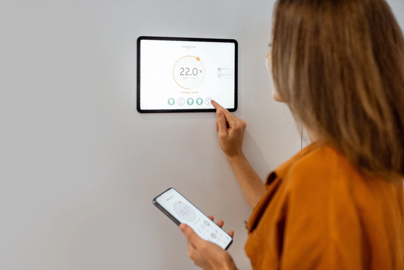 Foto di una donna che imposta un termostato.